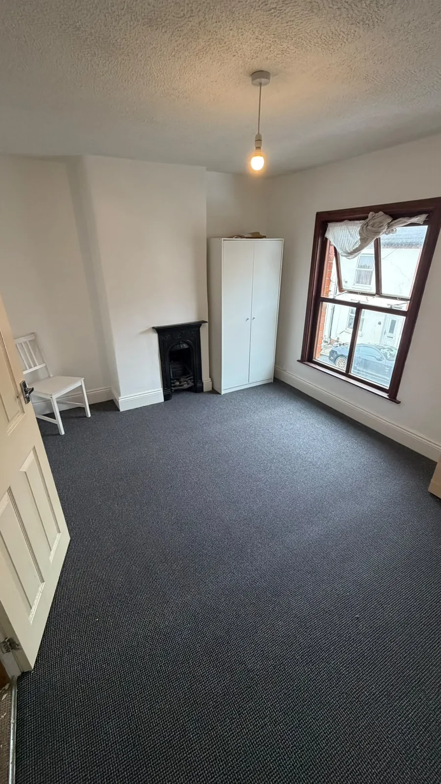 Dark grey carpet fitted across an empty room
