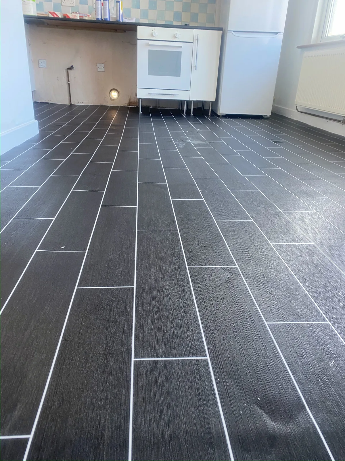 Dark tile-effect vinyl flooring in an empty room